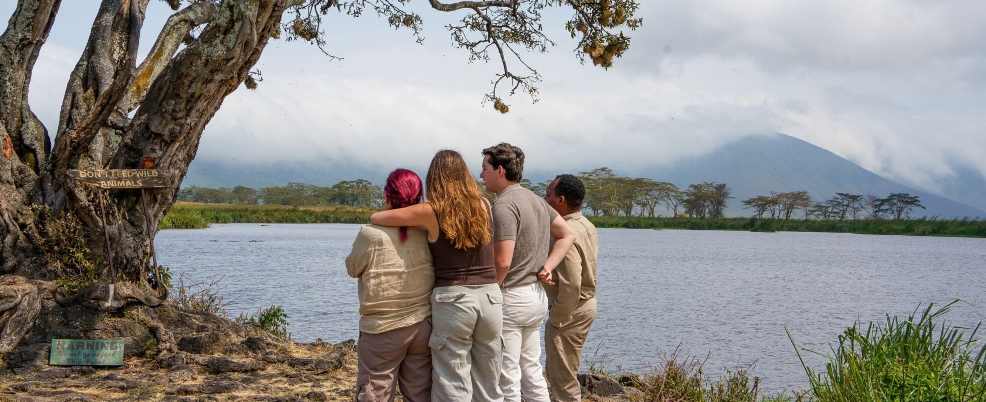 Cuatro personas que contemplan la naturaleza cogidas del brazo.
